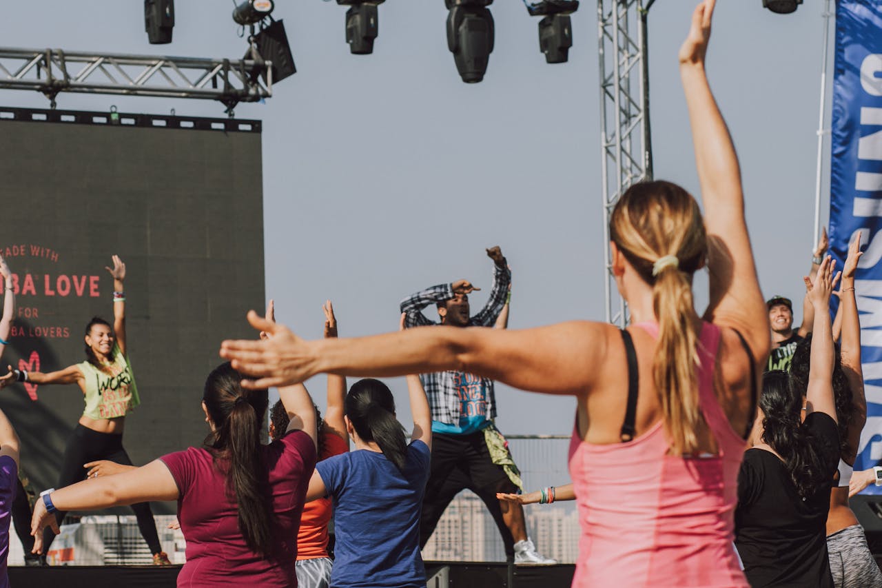Group of people participating in an energetic outdoor Zumba session led by an instructor.